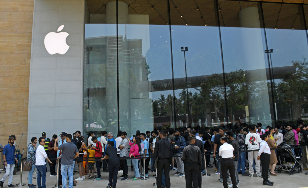 People are seen standing in a queue to enter the the Apple